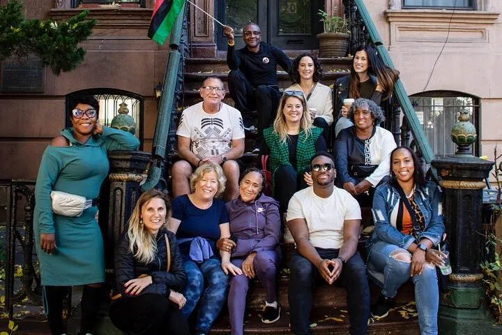 Group sitting on brownstone stoop steps on a New York architecture tour of Harlem