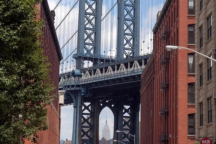Manhattan Bridge tower framed between brick buildings in DUMBO on a New York architecture tour of Brooklyn