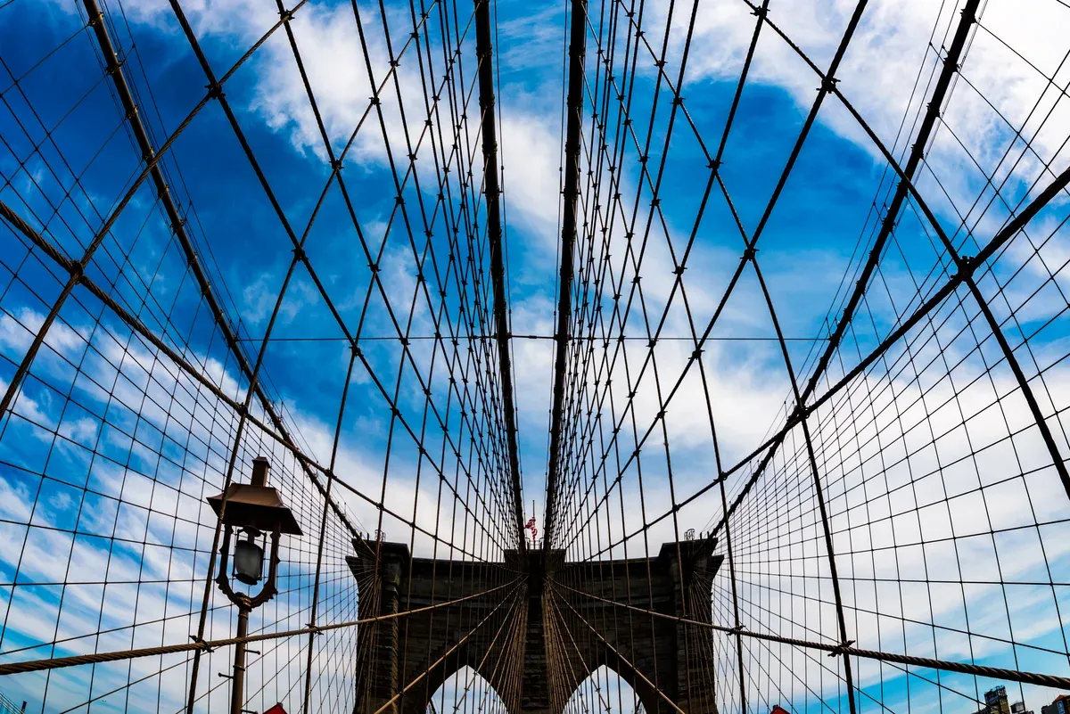 The Brooklyn Bridge tower with its web of suspension cables fanning out against the sky, on a New York architecture tour
